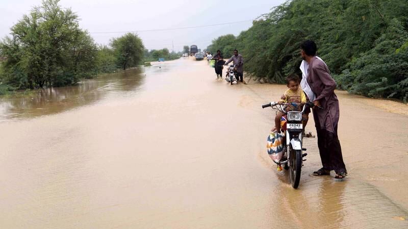 Residents make their way through a flooded area after heavy rains in Dera Ismail Khan.  EPA 