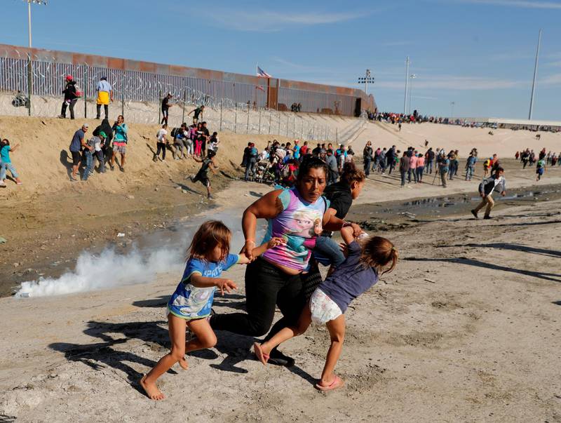 Maria Meza, a 40-year-old migrant woman from Honduras, part of a caravan of thousands from Central America trying to reach the United States, runs away from tear gas with her five-year-old twin daughters Saira Mejia Meza, left, and Cheili Mejia Meza, right, in front of the border wall between the US and Mexico, in Tijuana, Mexico, on November 25, 2018. Reuters