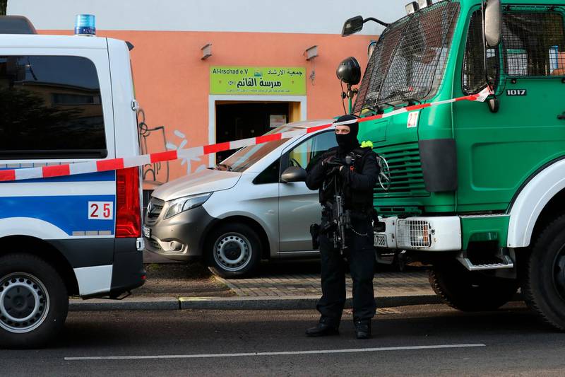 A police officer stands between utility vehicles in front of the Al-Irschad association in Berlin, Germany.  AP