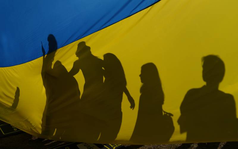 A family poses for a photograph in front of a Ukrainian flag opposite Downing Street in London. AP