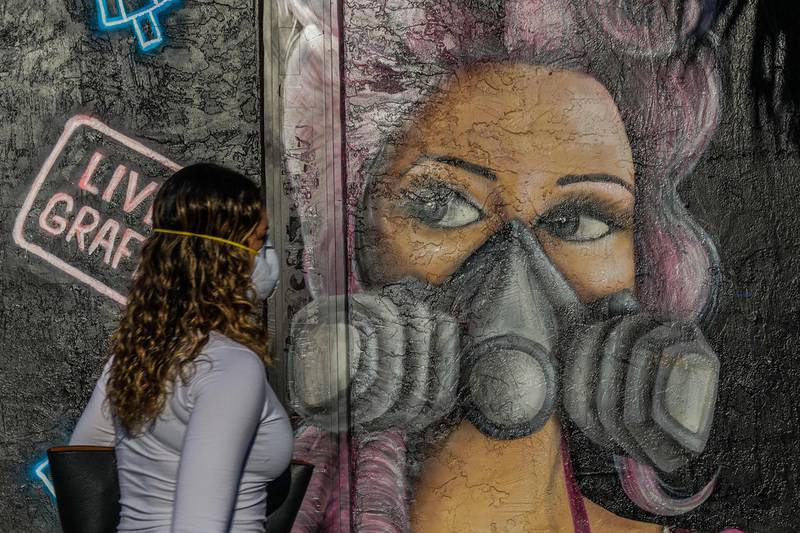 A woman walks past a closed shop with a mural in a deserted Wynwood Art District in Miami. AFP