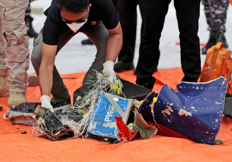 Investigators inspect debris found in the waters off Java Island around where a Sriwijaya Air passenger jet crashed, at Tanjung Priok Port in Jakarta, Indonesia. Indonesian divers on Sunday located parts of the wreckage of the Boeing 737-500 in the Java Sea, a day after the aircraft with dozens of people onboard crashed shortly after takeoff from Jakarta. AP Photo