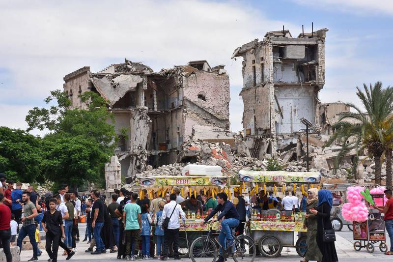 Syrians gather in front of the Citadel of Aleppo on the third day of Eid al-Fitr holiday as coronavirus restrictions are eased amid the COVID-19 pandemic, in northern Syria on May 26, 2020.  / AFP / -
