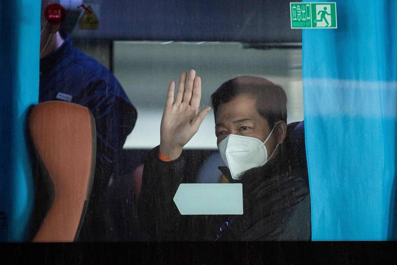 A member of the WHO team investigating the origins of the Covid-19 pandemic waves after boarding a bus following their arrival at a cordoned-off section in the international arrivals area at the airport in Wuhan. AFP