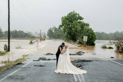 A stranded bride and groom rescued by helicopter on Saturday to get them to the church on time, kiss in front of a flooded bridge that had blocked their five-minute drive into town, in Port Macquarie, Australia. Reuters