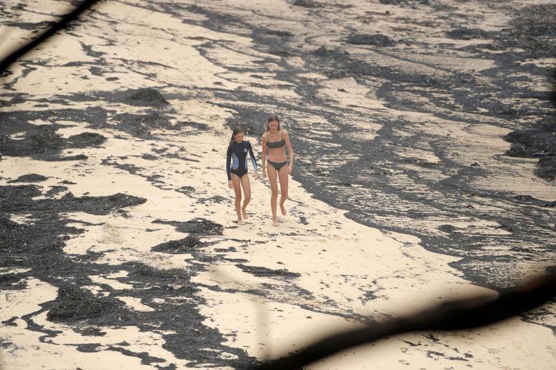 Girls walk past ash washed up on a beach where people took shelter during a fire on New Year's Eve in Mallacoota, Australia. Reuters