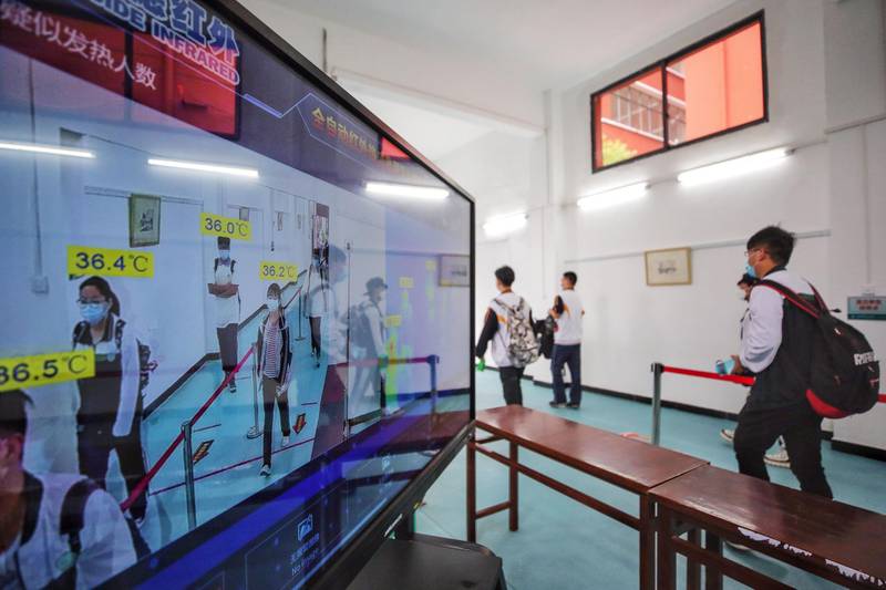 High school senior pupils walk past a thermal scanner as schools reopen in Wuhan in China's central Hubei province.  AFP