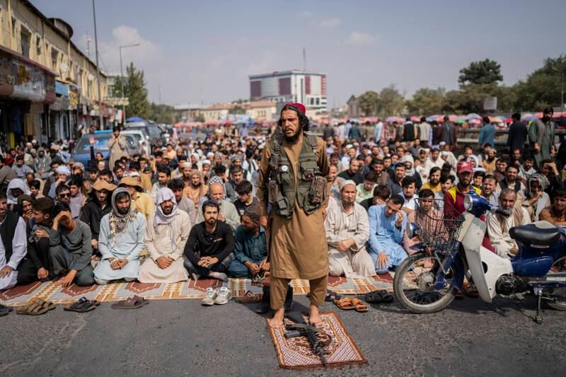A Taliban fighter and a group of Afghan men attend Friday prayers in Kabul. AP Photo