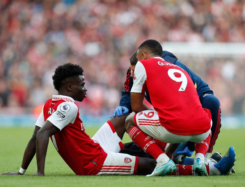Arsenal midfielder Bukayo Saka speaks to striker Gabriel Jesus as he is treated by a member of the medical staff after picking up an injury. AFP