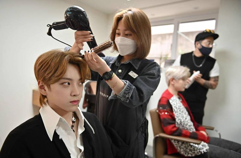 Member Jang Jun-ho, left, having his hair done at a beauty salon in Seoul ahead of a promotional shoot. AFP