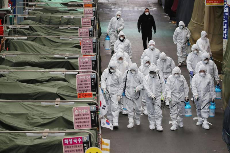 Market workers wearing protective gear spray disinfectant at a market in the southeastern city of Daegu as a preventive measure after the COVID-19 coronavirus outbreak.  AFP