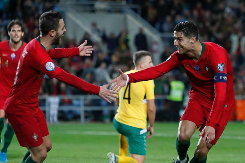 Portugal's Cristiano Ronaldo, right, celebrates with teammate Bernardo Silva after scoring his hat-trick during the Euro 2020 group B qualifier against Lithuania in Novmeber 2019. AP