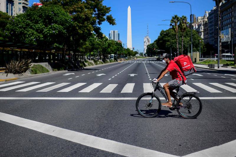 This picture taken on March 23, 2020 shows food delivery rider Dixon Abreu on a bicycle along the 9 de Julio Avenue in Buenos Aires, as he delivers meals due to an increase in orders as a result of the COVID-19 novel coronavirus. / AFP / Ronaldo SCHEMIDT
