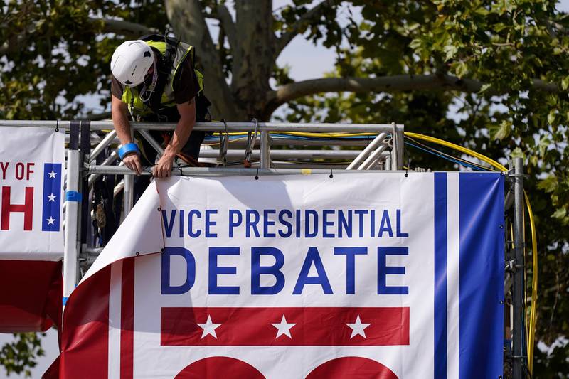 A worker hangs a banner as preparations take place for the vice presidential debate outside Kingsbury Hall at the University of Utah, Monday, Oct. 5, 2020, in Salt Lake City. The vice presidential debate between Vice President Mike Pence and Democratic vice presidential candidate, Sen. Kamala Harris, D-Calif., is scheduled for, Oct. 7. (AP Photo/Patrick Semansky)
