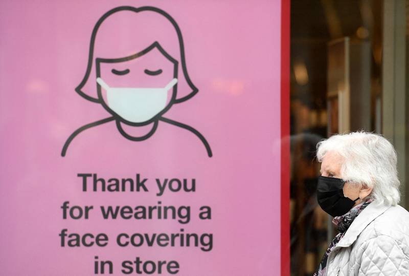 A member of the public wearing a face mask passes a sign asking shoppers to face coverings inside the store, in Cumbria, north west England. AFP