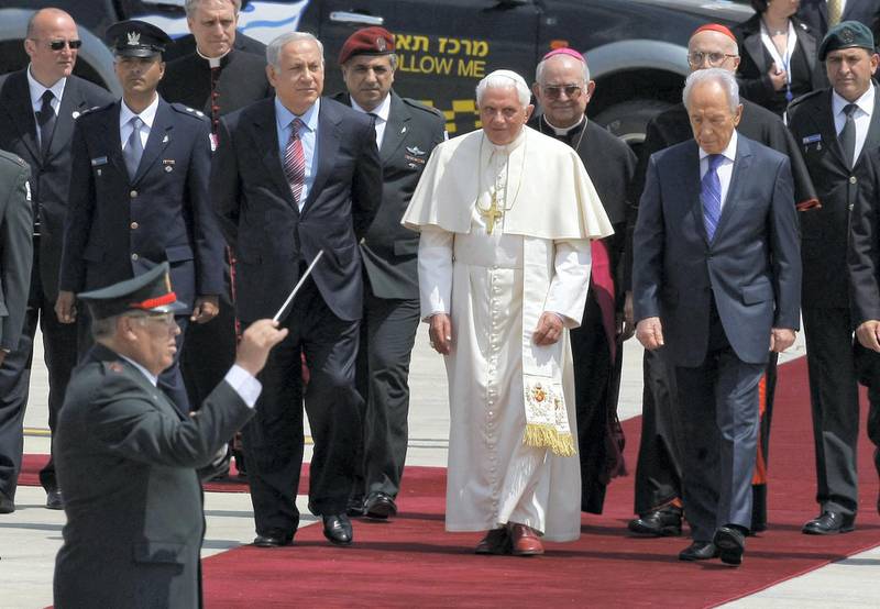 Pope Benedict XVI (C) walks between Israeli President Shimon Peres (R) and Israeli Prime Minister Benjamin Netanyahu (L) upon his arrival to Ben Gurion airport near Tel Aviv on May 11, 2009. Pope Benedict XVI pleaded for Israelis and Palestinians to reach a peace deal, in a speech he delivered at the start of a five-day trip to Israel and the occupied West Bank. AFP PHOTO/DAVID FURST (Photo by DAVID FURST / AFP)