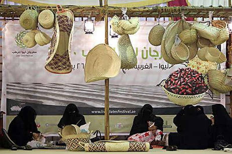Women weave straw baskets and mats out of palm leaves, a traditional handicraft in the UAE, at the Liwa Date Festival.