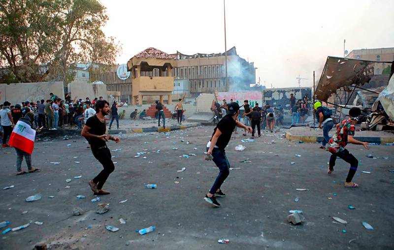 Protesters throw stones while security forces fire tear gas outside the governor's building during protests demanding better public services and jobs in Basra. AP Photo