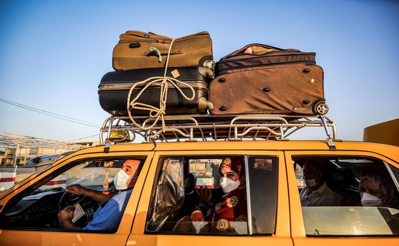 A Palestinian taxi driver and passengers, mask-clad due to the COVID-19 coronavirus pandemic, wait in a vehicle as they wait to cross to the Egyptian side of Rafah border crossing in the southern Gaza Strip, on September 27, 2020. (Photo by SAID KHATIB / AFP)