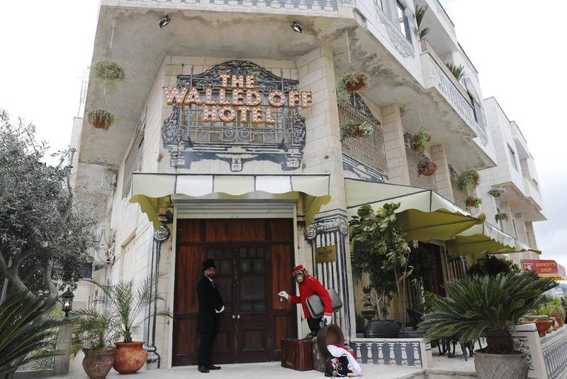 A bellboy stands outside street artist Banksy's newly opened Walled Off hotel in the Israeli occupied West Bank town of Bethlehem. Thomas Coex / AFP Photo
