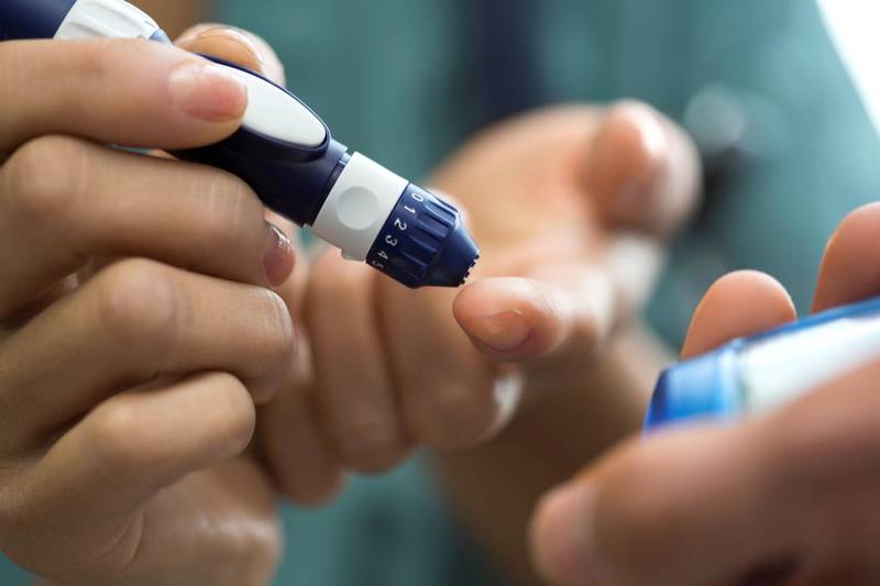 Close up nurse demonstrating insulin pen on finger