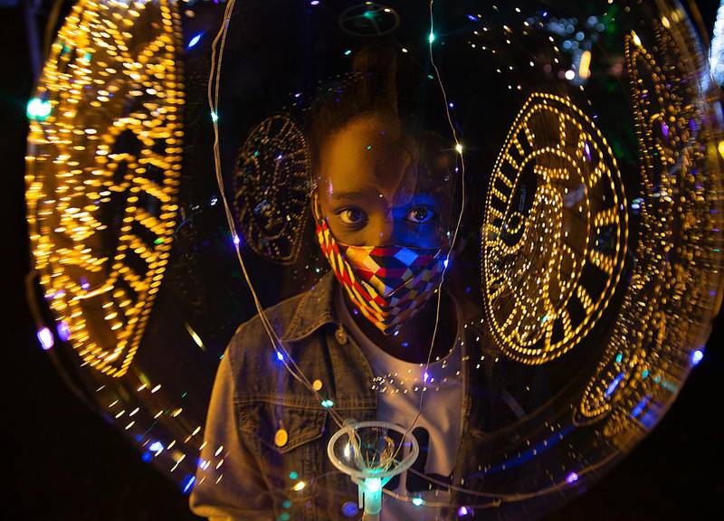 Christmas lights reflected on the ballon of a child wearing a face mask, at the Johannesburg Zoo's Festival of Lights, December 1. AP