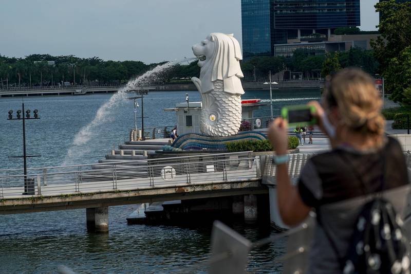 epa09134691 A woman takes a photograph of the Merlion statue in Singapore, 14 April 2021. The Ministry of Trade and Industry reported that the Singapore economy grew 0.2 percent for the first quarter of 2021, an increase from the contraction of 2.4 percent recorded in the previous quarter. The manufacturing and construction industries both recorded the highest percentage increases.  EPA/WALLACE WOON