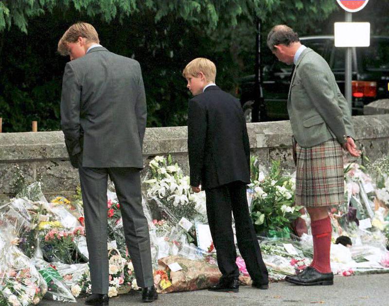 (FILES) This file photo taken on September 4, 1997 shows (L-R) Prince William, Prince Harry and their father the Prince of Wales stopping outside the gates to Balmoral Castle to look at the floral tributes. 
Twenty years ago on August 31, 1997, Britain's Diana, Princess of Wales, died in a high-speed car crash in Paris. / AFP PHOTO / PRESS ASSOCIATION / CHRIS BACON