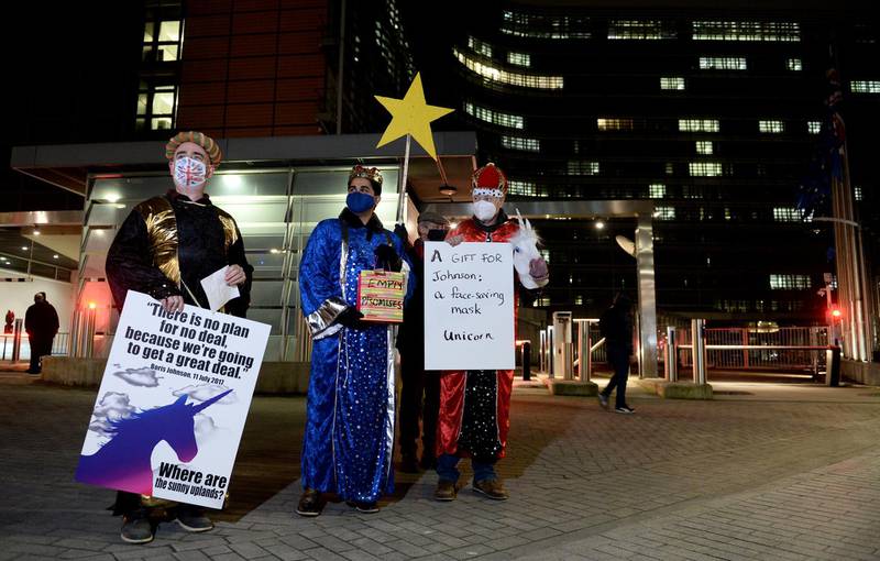 Carolers wearing protective face masks wait for Boris Johnson's arrival in Brussels. Reuters