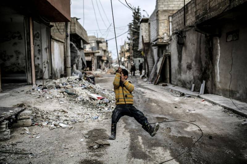 (FILES) In this file photo taken on March 24, 2015, a Kurdish Syrian boy plays among destroyed buildings in the Syrian Kurdish town of Kobane, also known as Ain al-Arab.  - 
 / AFP / YASIN AKGUL
