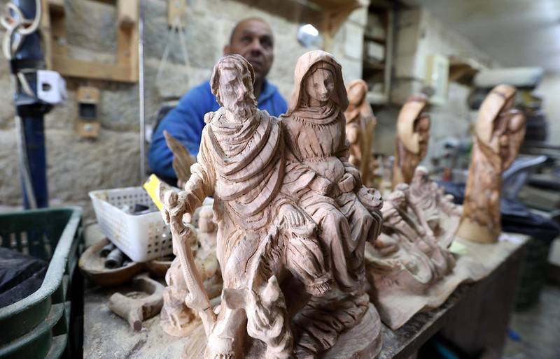 A Palestinian carpenter works on a wooden sculpture of Christian religious figures at a workshop in the West Bank city of Bethlehem.  EPA