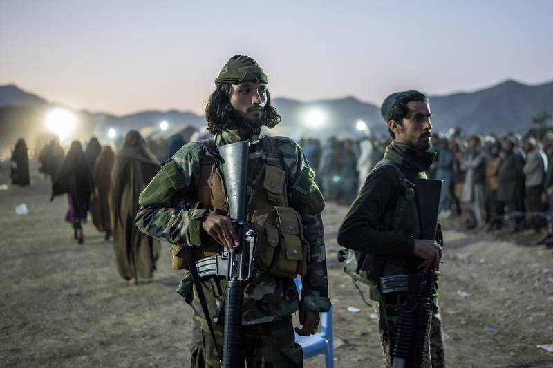 Taliban fighters stand guard as Afghan refugees line up to register in a camp near the Torkham Pakistan-Afghanistan border on Saturday. AP