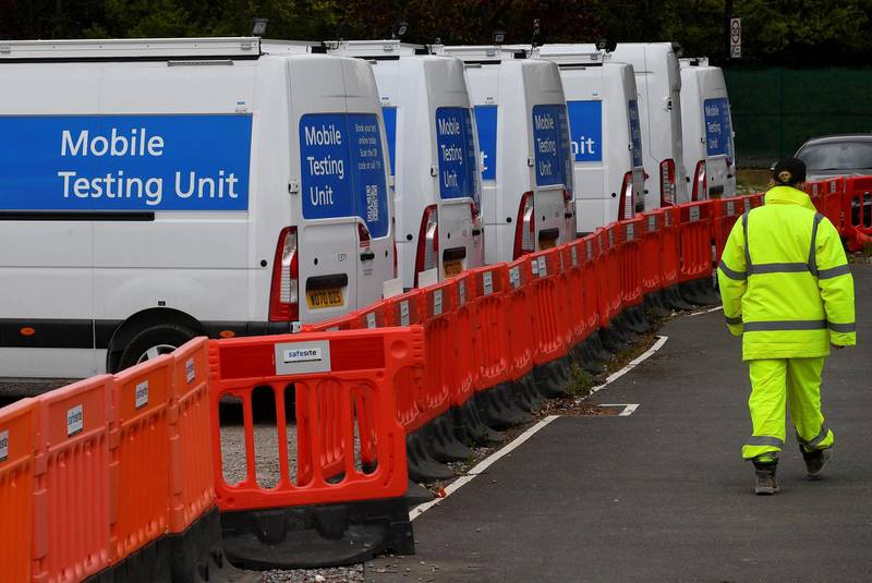 A worker walks past coronavirus disease mobile testing vehicles parked at a depot in London. Reuters