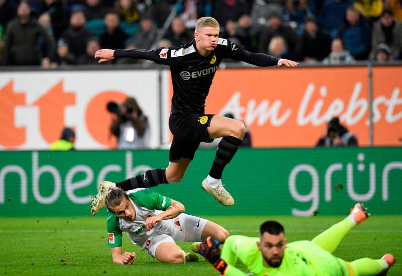 Erling Haaland jumps over Augsburg goalkeeper Tomas Koubek and defender Tin Jedvaj to score for Dortmund. AFP