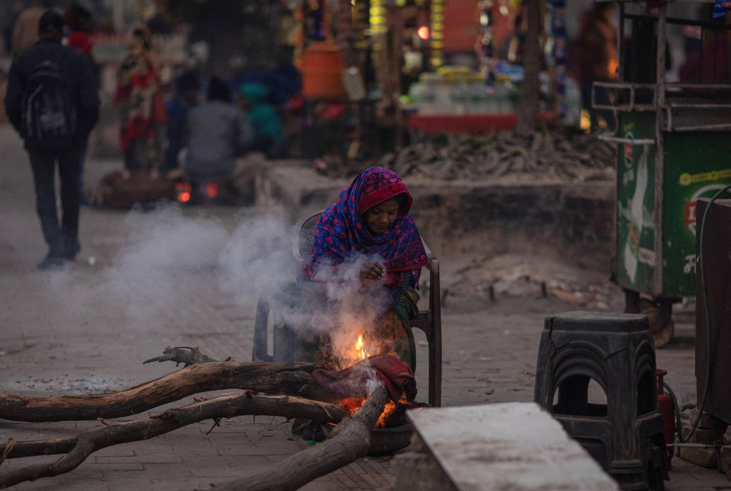 A woman tries to warm up next to her tea stall on Wednesday.  Reuters