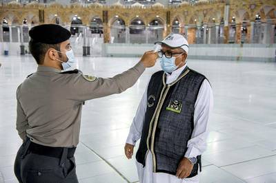 A security man checks the temperature of a worker as they work on raising the Kiswa, a silk cloth covering the Holy Kaaba, before the annual pilgrimage season, at the Grand Mosque in Mecca, Saudi Arabia. REUTERS