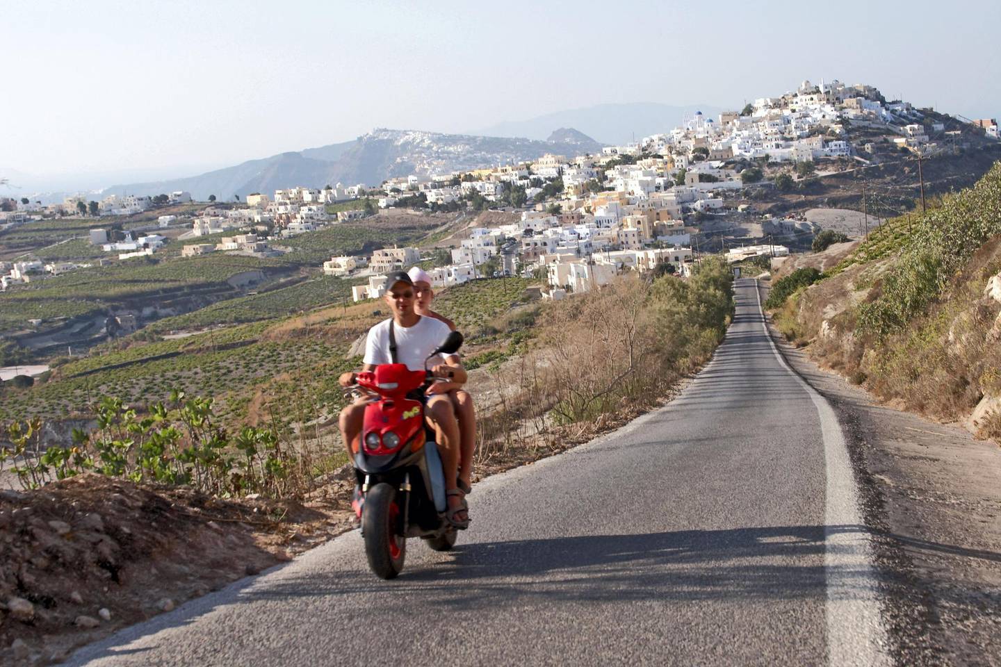 A6GMR0 View of Pyrgos or Pirgos with people on scooter motorbike or cycle Greek Island of Santorini or Thira Greece