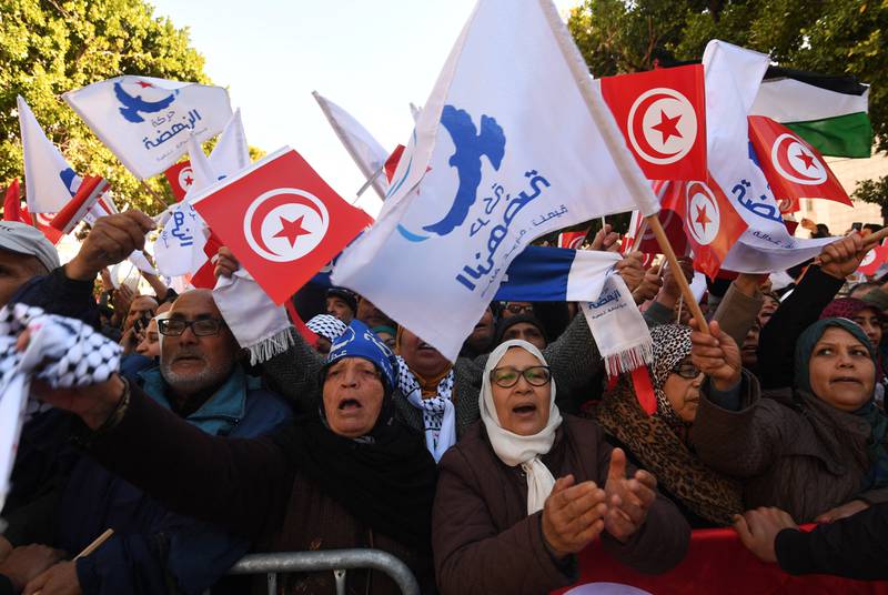 Tunisians wave their national flag and the flag of the Ennahda Islamist party as they gather on Habib Bourguiba Avenue in Tunis on January 14, 2018. AFP