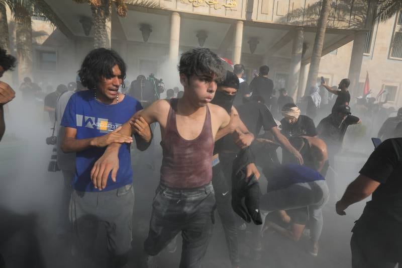 Supporters of Mr Al Sadr help injured protesters during clashes with riot police in Baghdad. EPA