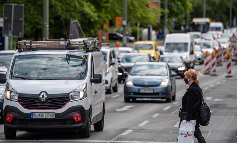 A woman wearing a face mask crosses in front of traffic in central Berlin on May 14, 2020, as a relaxation of lockdown restrictions in the capital has led to more cars on the road, amid the new coronavirus COVID-19 pandemic. (Photo by John MACDOUGALL / AFP)