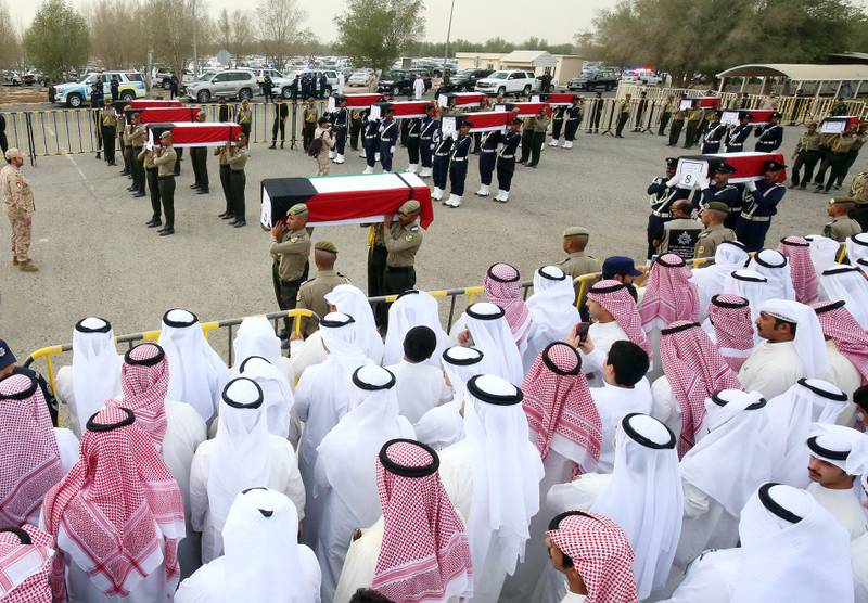 Mourners carry the coffins of nineteen Kuwaiti prisoners of war whose remains were recently found in a mass grave in Iraq and identified through DNA tests, during a funeral procession at a cemetery in Kuwait City on November 21. Photo: AFP
