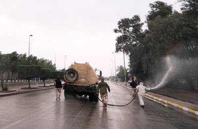 A soldier wearing a protective suit sprays disinfectants on a street. Reuters