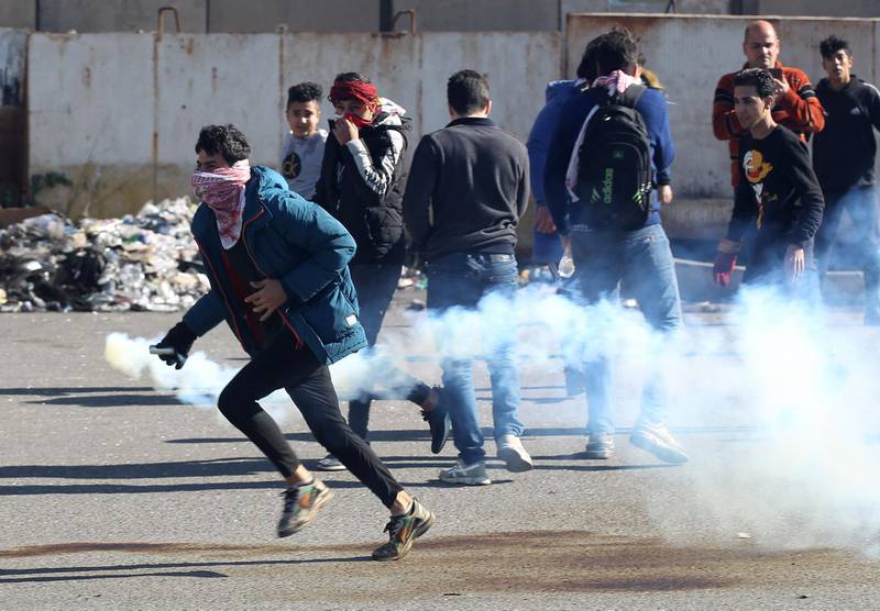 An Iraqi protester runs while carrying a tear gas canister fired by security forces amid clashes during an anti-government demonstration in Al-Khilani square in the capital Baghdad.  AFP