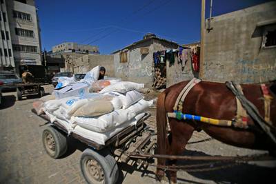 A Palestinian loads a cart with aid food provided by the UN's World Food Programme and its agency for Palestinian refugees, UNRWA, in the Gaza Strip's al-Shati refugee camp on May 15, 2019. - Palestinians are marking the 1948 Nakba, or "catastrophe", which left hundreds of thousands of Palestinians displaced by the war accompanying the birth of the Jewish state. (Photo by MOHAMMED ABED / AFP)