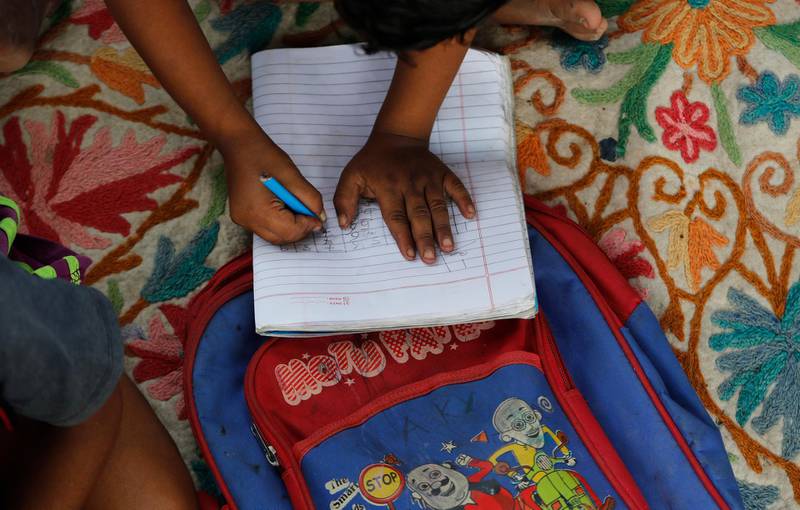A child practices writing numbers on a sidewalk class in New Delhi, India, on Sept. 3, 2020. An Indian couple, Veena and her husband Virendra Gupta, is conducting free classes for underprivileged children on a sidewalk in New Delhi with the goal to keep them learning and not left behind when schools reopen. It all began when Veena's maid complained that with schools shut, children in her impoverished community were running amok and wasting time. As most schools in India remain shut since late March when the country imposed a nationwide lockdown to curb the spread of COVID-19, many switched to digital learning and taking classes online. (AP Photo/Manish Swarup)