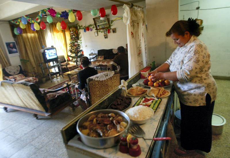An Iraqi lady stands in her kitchen as other family members sit in the living room watching television, as she prepares the New Year's Eve diner at their home in an apartment block in the al-Sadun district of Baghdad, 31 December 2005. The last six months of 2004 proved the deadliest period for US forces in Iraq despite the formal end of the US-led occupation in June, with a total of 503 soldiers killed, figures showed today. AFP PHOTO/AHMAD AL-RUBAYE (Photo by AHMAD AL-RUBAYE / AFP)