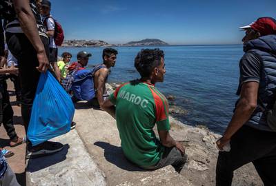 A Moroccan migrant wearing a Moroccan football team T-shirt sits after trying to cross the border between Morocco and the Spanish enclave of Ceuta. AFP