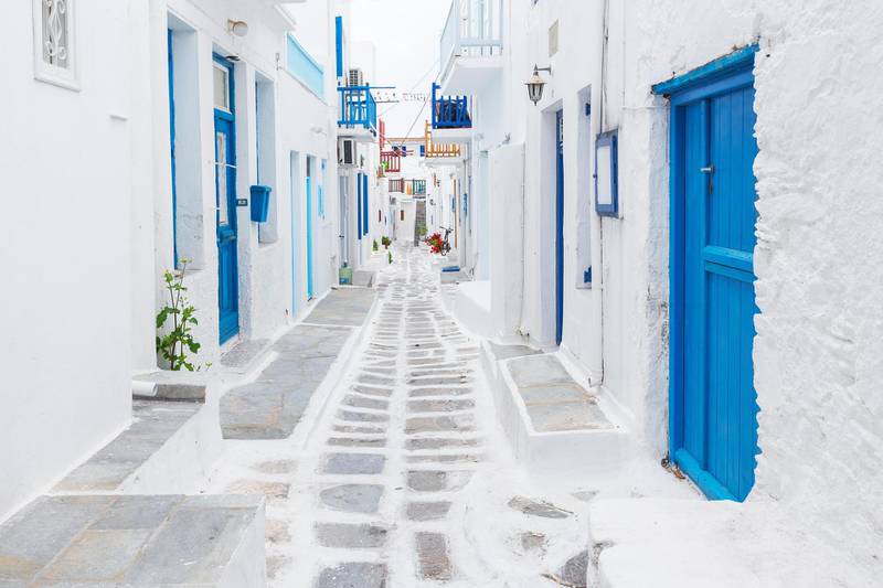 HRBXTE Traditional white painted Mykonos streetview with blue door, Greece. Zoltan Gabor / Alamy Stock Photo