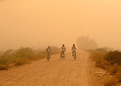 Boys ride their bicycles in the Basra gloom.