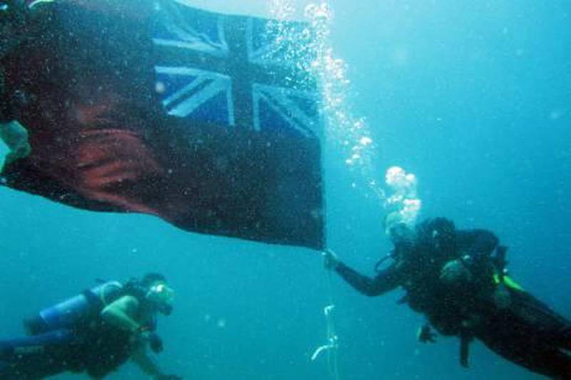 Ajman, April 8, 2011 - Jane Taylor (L) swims by as Craig Dunn (R) holds a Union Jack Red Ensign flag eight meters above the wreckage of the MV Dara, a British merchant ship that sunk in 21 meters of water off the coast of Ajman with 819 people on board with 238 killed on April 8, 1961. Divers from Abu Dhabi, Dubai and Sharjah participated in securing the flag to the ship as a memorial on April 8, 2011. (Courtesy of Jane Taylor) 